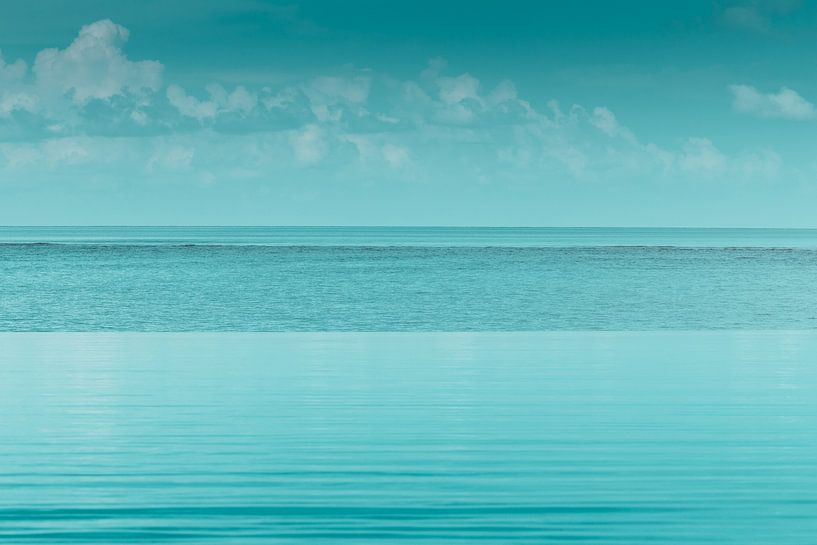 Water surface of an infinity pool in front of blue sea by Besa Art