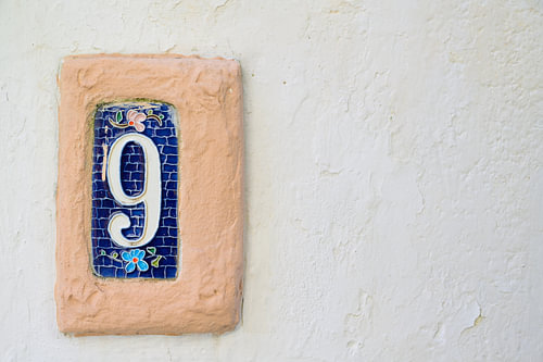 Plaque en céramique portant le numéro 9, fixée à un mur