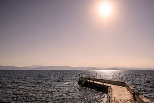 Zon met weerspiegeling en pier