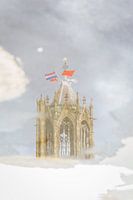 De Domtoren van Utrecht weerspiegeld in een plas regenwater.
