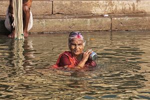 Hindoe vrouwenpelgrim neemt een bad in de Heilige rivier de Ganges van Tjeerd Kruse