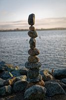 De kunst van het balanceren van rotsen (stenen) met water, wolken en lucht op de achtergrond