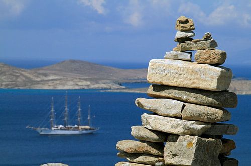 Zeilschip achter gestapelde stenen aan de kust