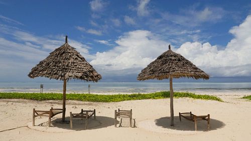 Wit strand op tropisch eiland met bamboo parasols