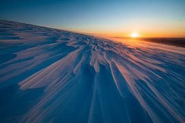 Ondergaande zon boven een sneeuwvlakte