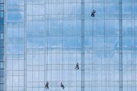 4 glazenwassers op blauw glazen gevel