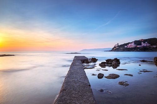 Betonnen pier, rotsen en zee bij zonsondergang. Castiglioncello