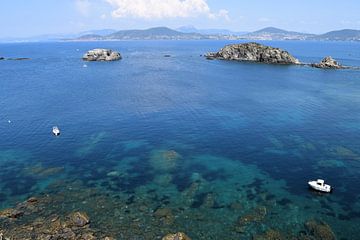 Blauwe baai in de Middellandse zee met wit klein motorbootje. Rotsen in de baai, kleine eilandjes van Studio LE-gals