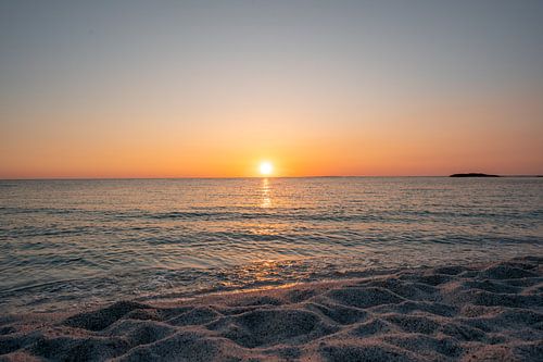 Risottorijst op het strand van Is Arutas in Sardinië bij zonsondergang met glinsterende zee en stenen