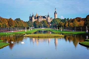 Schweriner kasteel gezien vanuit het park met waterkanalen, reflecties, beelden en bomen met gekleur