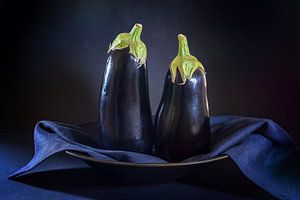 Twee aubergines op een bord met een donkerblauw servet ertegenaan