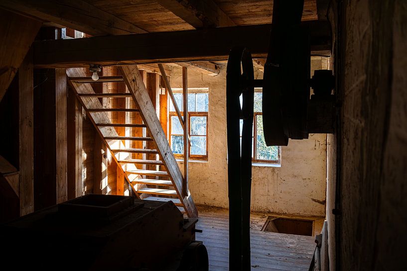 Pièce abandonnée avec escalier en bois et jeu de lumière dans un ancien moulin par Infinite Decay