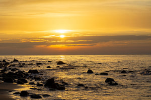 Sonnenuntergang am Strand mit großen Felsen im Wasser an der Ostsee auf Rügen