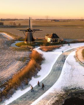 Skating near a windmill in a winter landscape von Ewold Kooistra