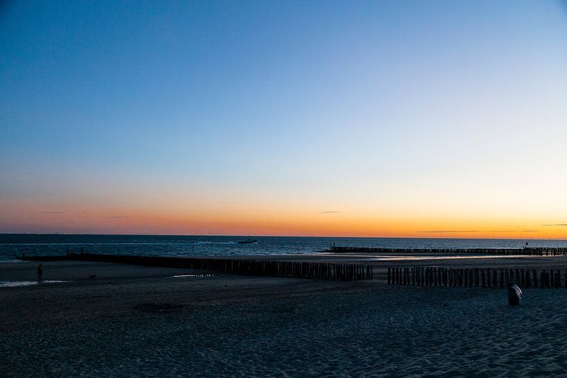 photo de plage capture la lumiere chaude d'un coucher de soleil poteaux en bois par Manon van Bochove