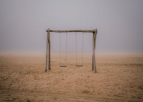De eenzame schommel op het strand in de mist