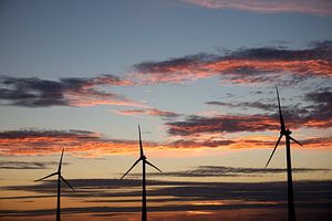 Sonnenuntergang mit drei Windturbinen, die zu einem Windpark gehören