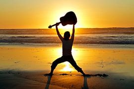 Guitar player with his guitar on the beach at sunset by Eye on You