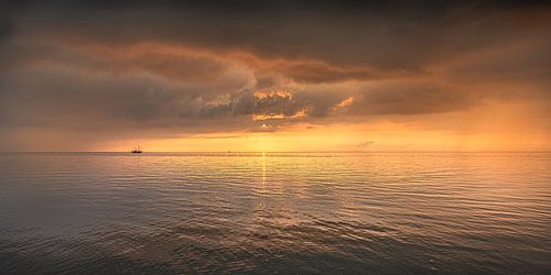 Sfeerbeeld van een vissersbootje op het Wad tussen twee kleine buitjes in