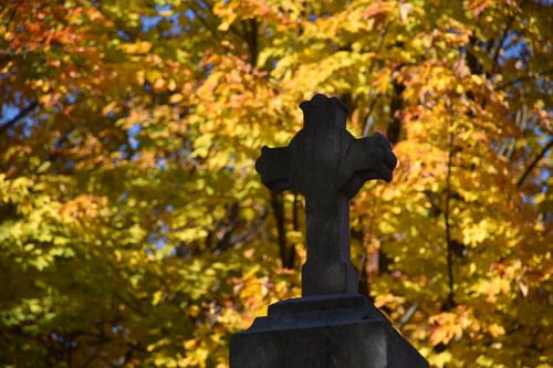 Ein Kreuz auf dem Kirchhof im Herbst