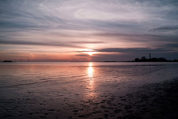 Prachtige zonsondergang met weerspiegeling op het zand