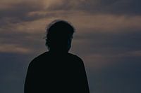Männliche Silhouette vor den Wolken