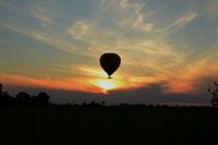 heteluchtballon tijdens zonsondergang in de polders van Nederland