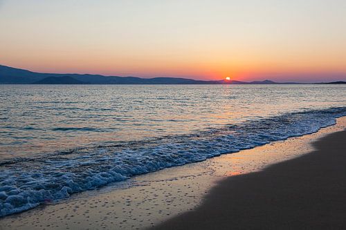 Zonsondergang met rustige zee op het strand van Naxos, Griekenland.