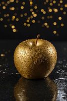 Golden apple on wet black background