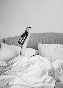 Champagner im Bett - Schwarz-Weiß-Fotografie - Frau mit Alkoholflasche in der Hand Fotografie