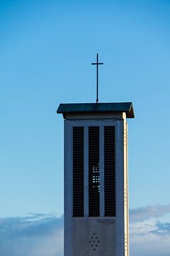 Kirchturm mit Kreuz auf dem Dach und blauem Himmel im Hintergrund von adventure-photos