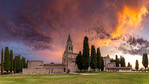 Basilika von Aquileia unter einem wolkenverhangenen, farbenprächtigen Morgenhimmel