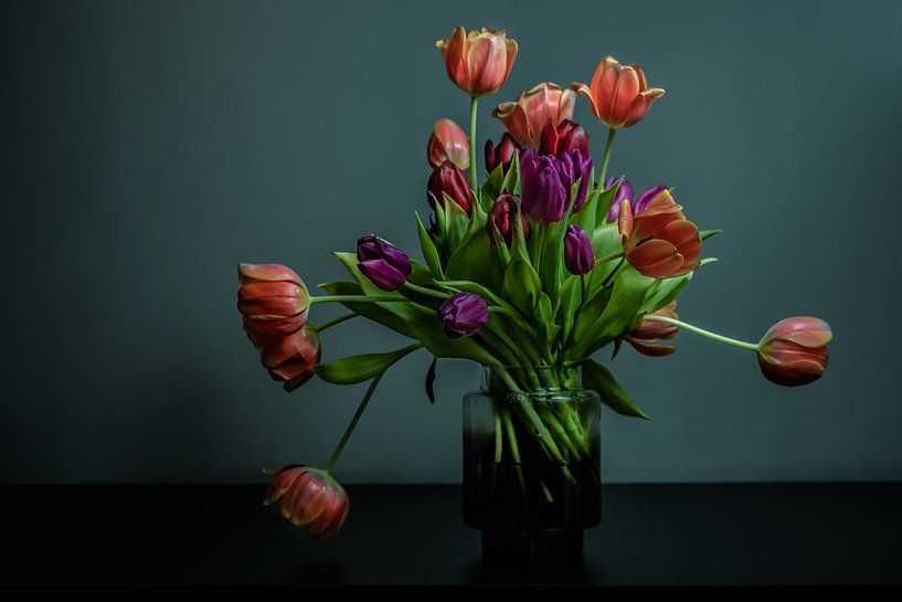 Bunch of tulips in bloom in a vase of glass against a dark background by Atelier Liesjes