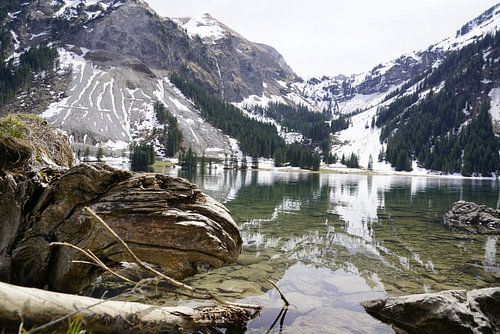 De Vilsalpsee in het Tannheimer Tal met spiegelend water en een alpenberglandschap op de achtergrond.