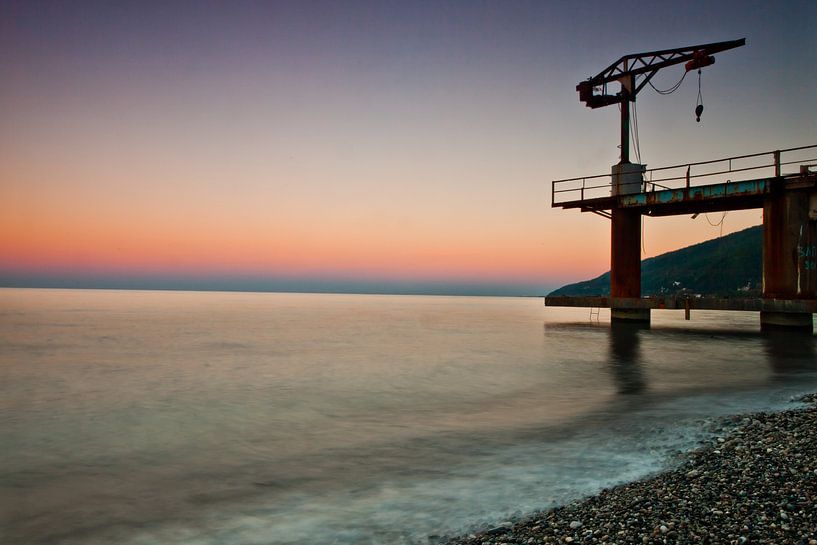 Zonsondergang over de zee, paarse en roze kleuren, een kleine kraanvogel op de pier van Michael Semenov