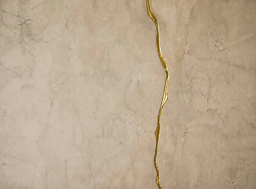 Gouden kintsugi-ader op zacht kalkpleisterwerk