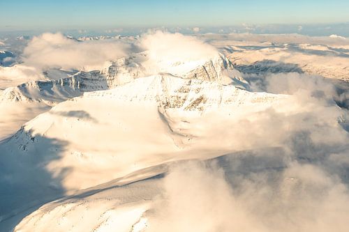 Luchtfoto vanuit een vliegtuig hoog boven de besneeuwde bergen in Noord-Noorwegen