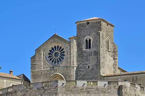 Une vieille église avec une rosace et un clocher, sous un ciel d'un bleu éclatant.