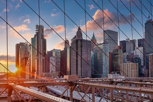 De skyline van New York van de Brug van Brooklyn bij zonsondergang in de Winter met wolken in de hem