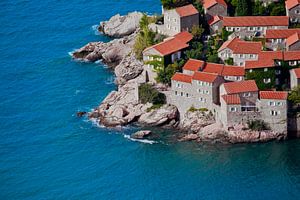 Alte Häuser mit roten Ziegeln und hellblauem Meer in der Nähe von Montenegro, Sveti Stefan. von Michael Semenov