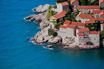 Oude huizen bedekt met rode tegels en helderblauwe zee close-up Montenegro, Sveti Stefan. van Michael Semenov