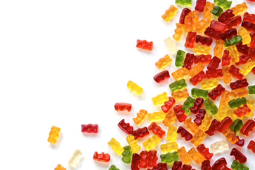 Eckhintergrund aus bunten Fruchtgummibonbons, isoliert mit kleinem Schatten auf weißem, großzügigem 