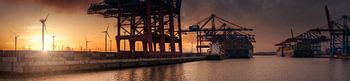 Container terminal at sunset with wind turbines
