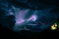 Bolt of lightning cuts through the sky near a castle in the mountains