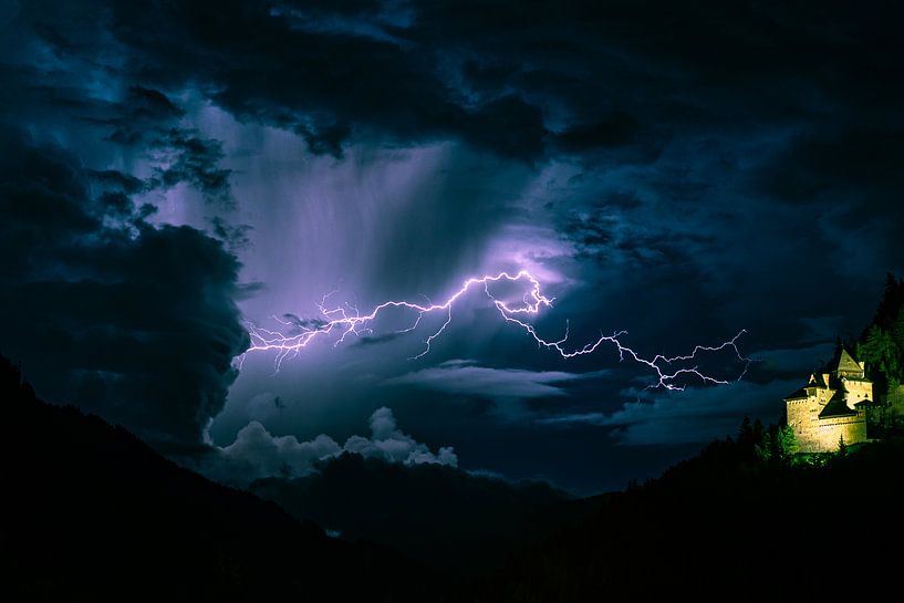 Blitz klärt den Himmel in der Nähe einer Burg in den Bergen von Menno van der Haven