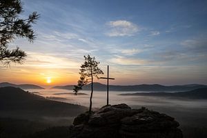 Der Rötzenfels, eine Landschaftsaufnahme von einem Sandsteinfelsen mit Kreutz und Baum, Sonnenaufgan