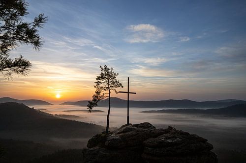 De Rötzenfels, een landschapsopname van een zandsteenrots met een kruis en een boom, zonsopgang met 