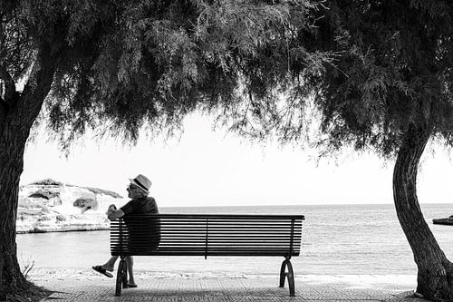 Homme sur un banc entre palmiers sur la plage et mer dans les Pouilles, Italie