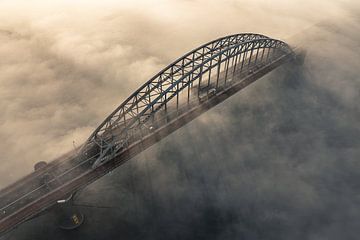 Forenzen op de Waalbrug boven de mist bij zonsopkomst van Norbert Kolster van Highvisual