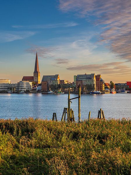 Uitzicht over de Warnow naar de Hanzestad Rostock in de avond van Rico Ködder